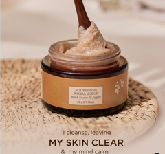 Facial scrub jar with spatula scooping gritty paste, black sesame & jaggery.