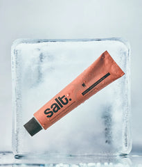 Peach toothpaste tube with black cap, angled view