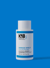 K18 Damage Shield pH protective shampoo bottle, white with blue stripe and label