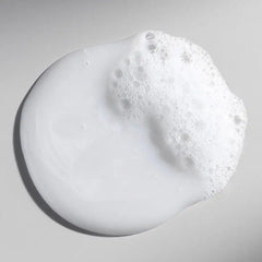Shampoo lather on skin-like surface, white foam bubbles and creamy texture.