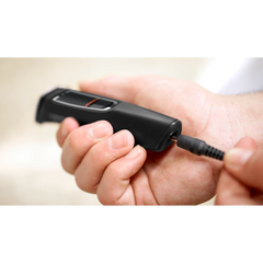 Black all-in-one hair and face trimmer being held with power cord attached