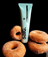 Toothpaste tube, light blue with black cap, with several donuts nearby