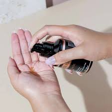 Marula oil serum bottle with pump held near hands