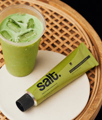Salt whitening toothpaste tube and mint-green gel in a cup