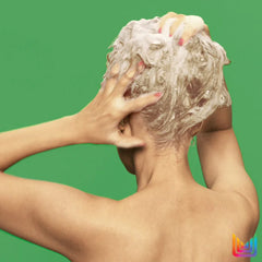Hands lathering shampoo foam into hair, foamy blonde strands visible