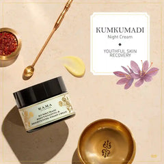 Night cream jar with black cap beside gold bowl and gold applicator spoon.