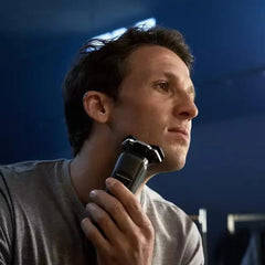 Man shaving with electric shaver held to chin