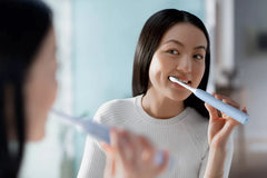 Light blue Philips Sonicare electric toothbrush in mouth, held by a person