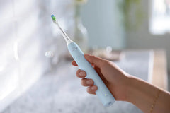 Light blue Philips Sonicare electric toothbrush held close, brush head visible