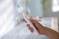Sugar Rose electric toothbrush with bristles, held in hand