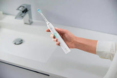 Electric toothbrush in hand, white handle with teal bristles