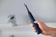 Hand holding Philips Sonicare ProtectiveClean 5100 electric toothbrush, blue handle