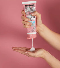 Hydrate Expectations body serum in hands, with white lotion drop