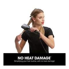 Black hot air hair styler in hand, pointed nozzle near hair