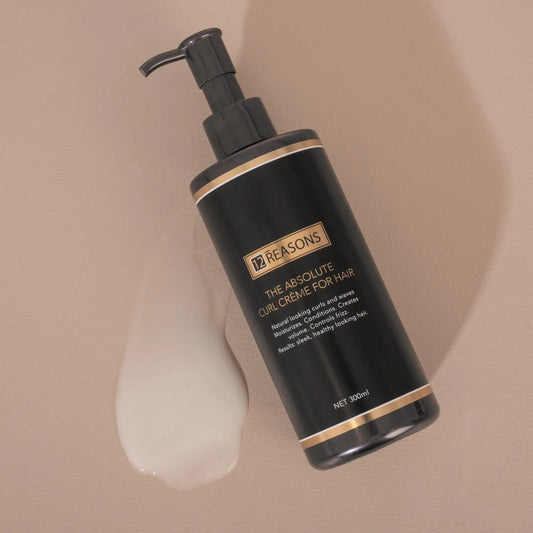 Hair curl creme bottle with black pump and dollop of cream on surface