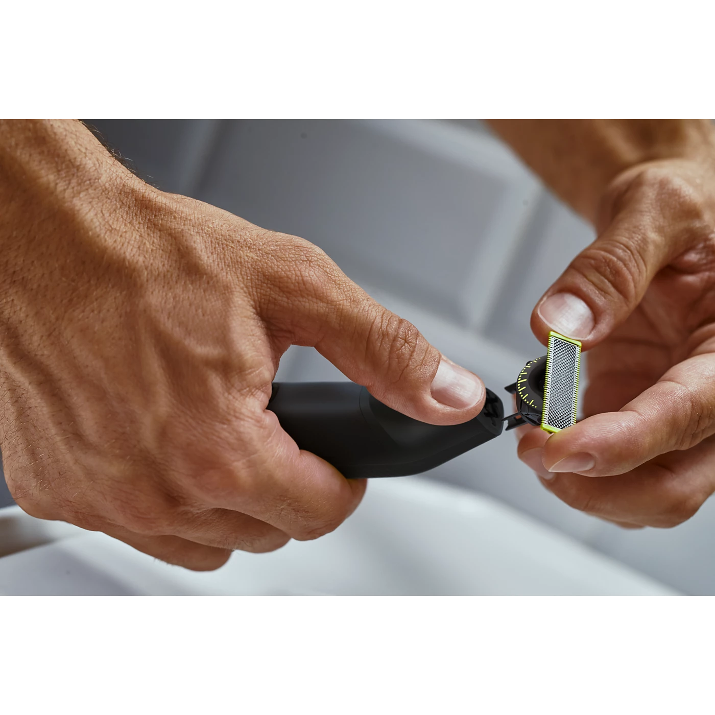 Electric OneBlade trimmer in use, cutting head against skin