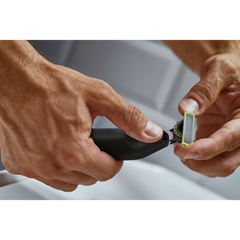 Electric OneBlade trimmer in use, cutting head against skin