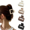 Small square hair claw clips with frosted finish; one clip worn on dark hair.