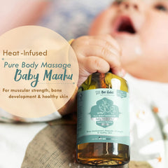 Baby massage oil bottle with silver cap near a person’s hand and amber oil