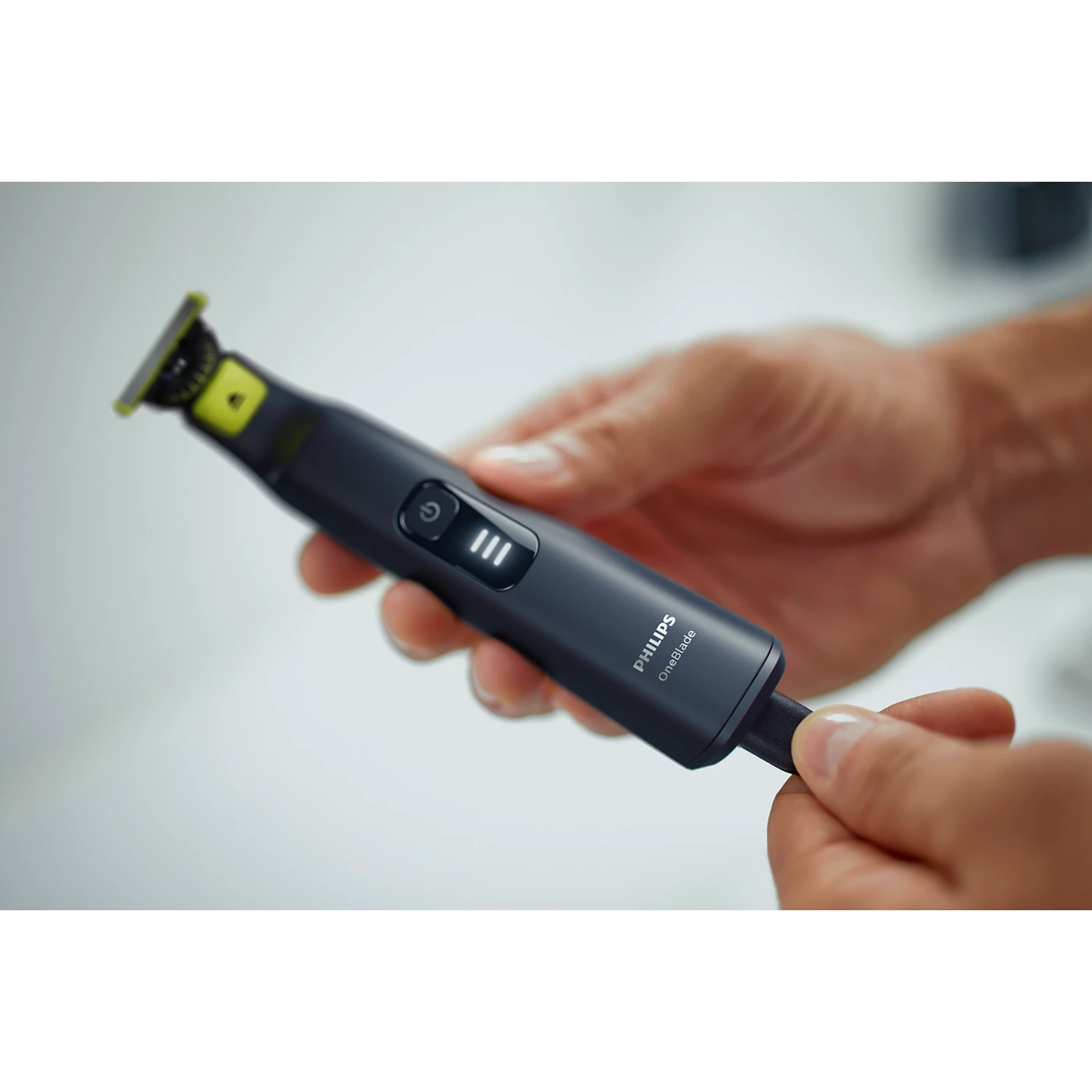 Philips OneBlade Pro trimmer held in hand with power and setting buttons