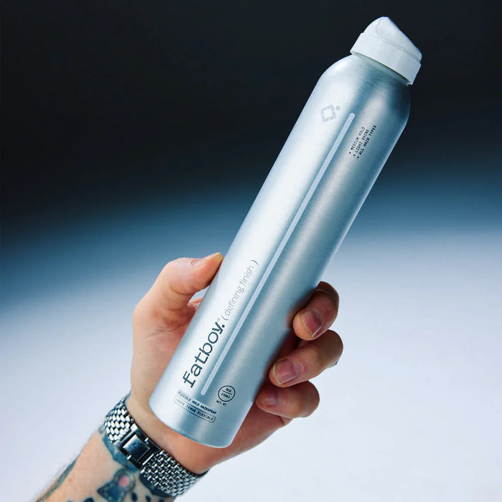 Light blue hairspray bottle held in hand, white flip-top cap