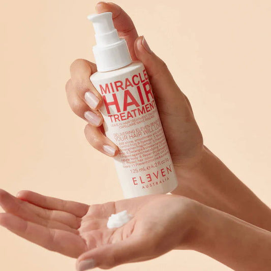 Eleven Australia Miracle Hair Treatment pump bottle with white lotion on hand