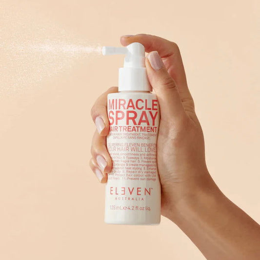 Eleven Australia Miracle Spray hair treatment bottle with white pump, held in hand