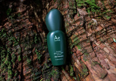 Green night serum bottle on tree bark, Ae botanicals branding
