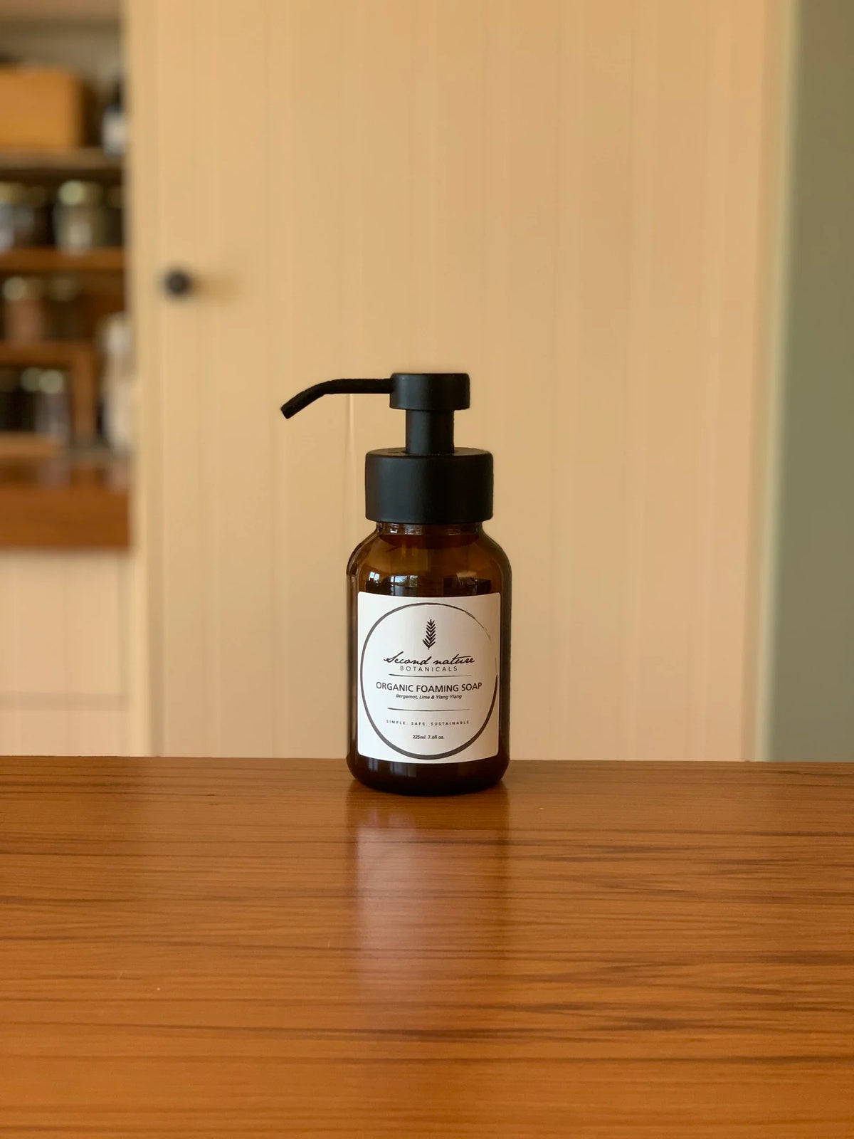 Foaming soap dispenser bottle with amber liquid and black pump, botanical label
