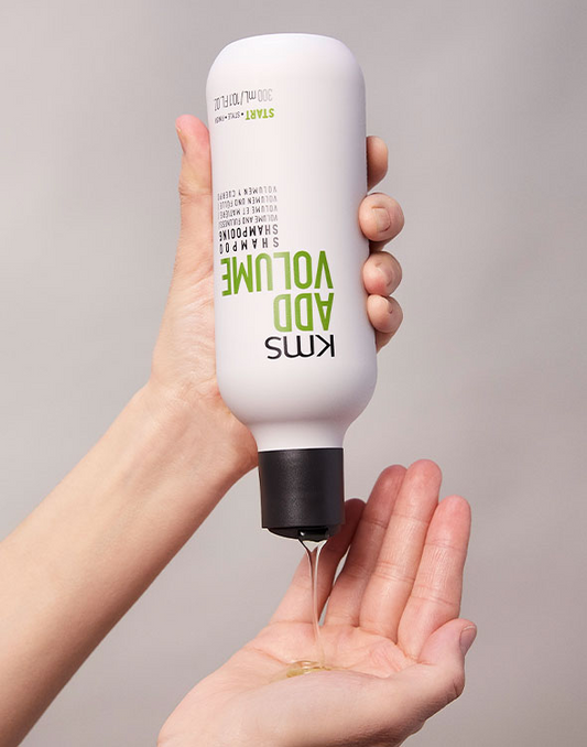 Shampoo bottle held in hand, showing back label text and barcode
