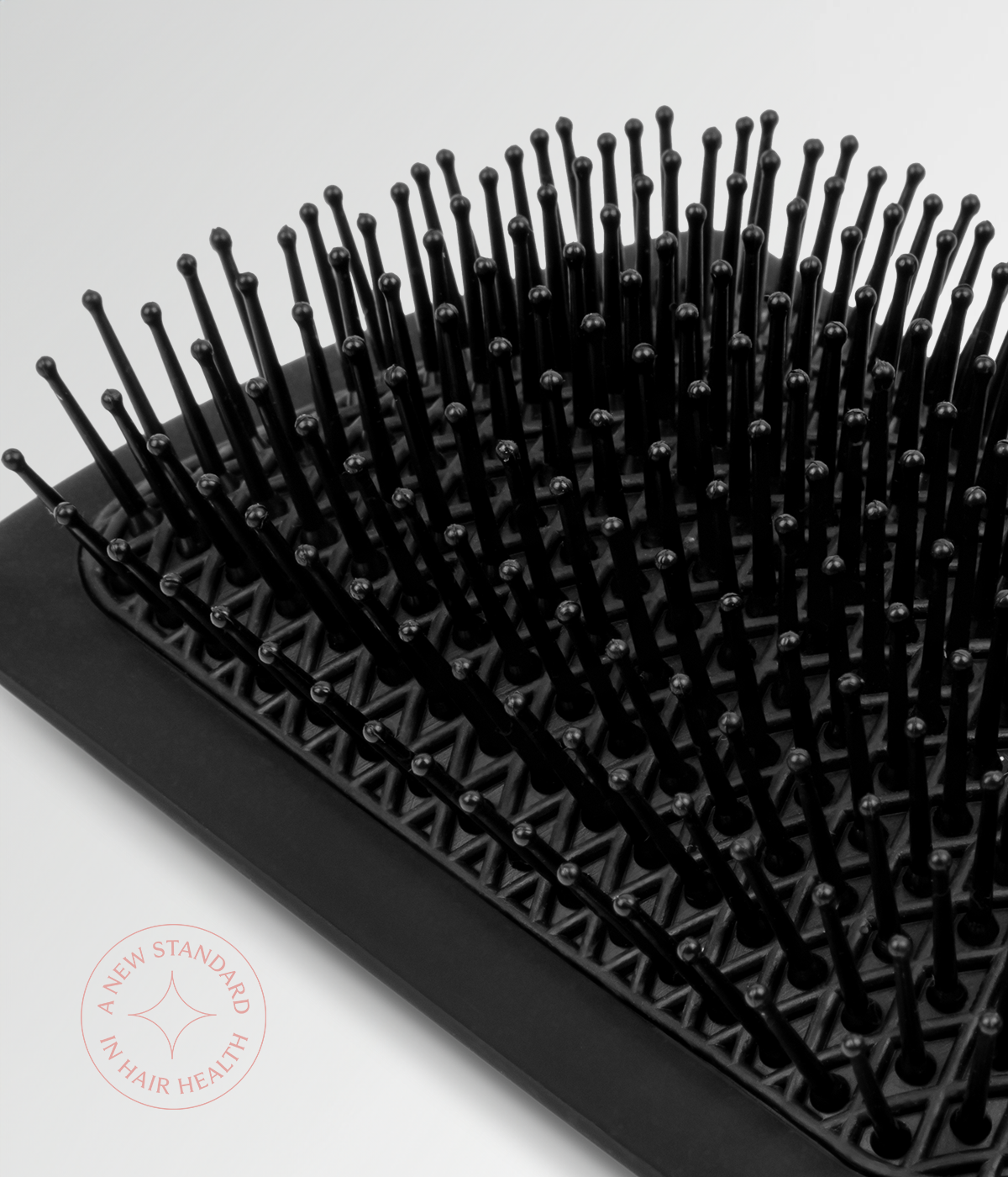 Black cushion hair brush showing dense rows of rounded pins on base