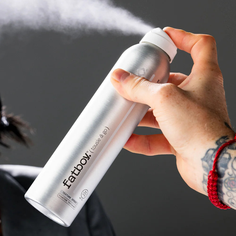 Fat Boy Tousle & Go 177ml spray can held in hand, silver finish with white cap