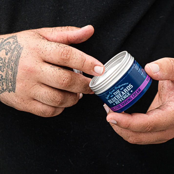 Hands holding a blue shaving cream jar with silver lid and purple Classic Shaving Cream label