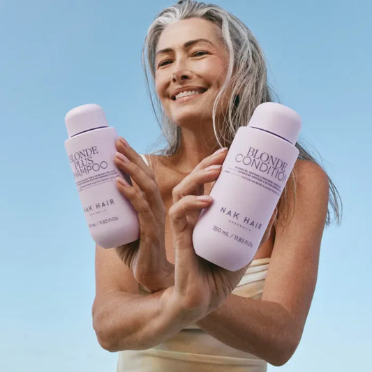 Blonde Plus shampoo and conditioner bottles in lavender, held by a person