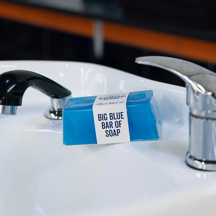 Blue bar of soap with white label, placed on a sink edge