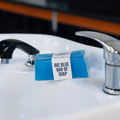 Blue bar of soap with white label, placed on a sink edge